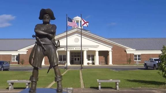 Statue of the Fairhope High School mascot in front of the school entrance and flags.